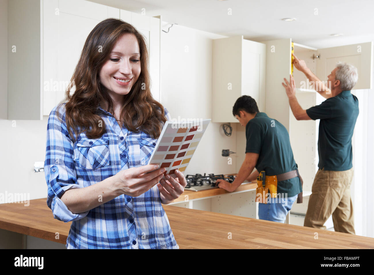 Woman Looking At Paint Chart In New Kitchen Stock Photo