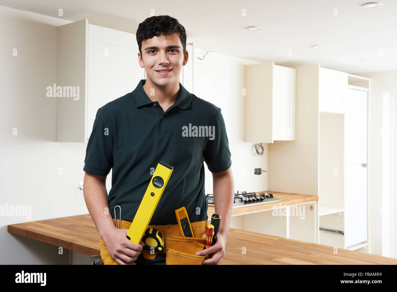 Apprentice Carpenter Installing Luxury Fitted Kitchen Stock Photo