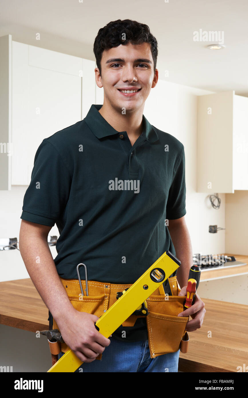 Apprentice Carpenter Installing Luxury Fitted Kitchen Stock Photo
