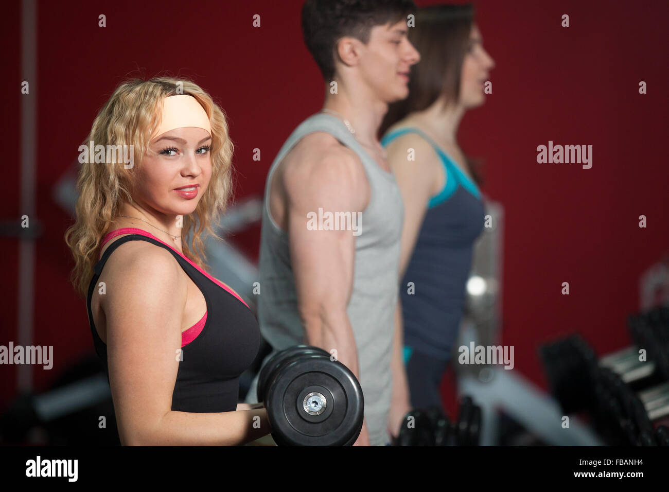 Group of sporty people do bodybuilding exercises with dumbbells in gym Stock Photo