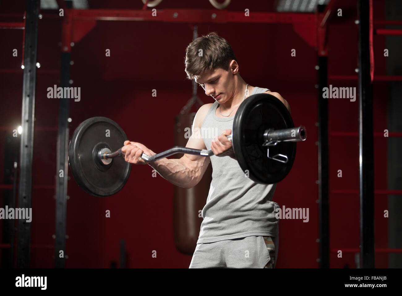 Young caucasian sportsman lifts barbell in fitness center Stock Photo