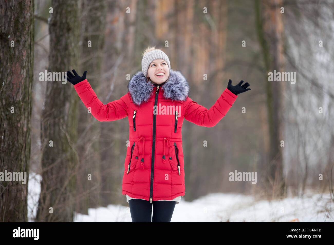 Happy beautiful girl in knitted hat and red winter coat, outdoors, expressing joy Stock Photo