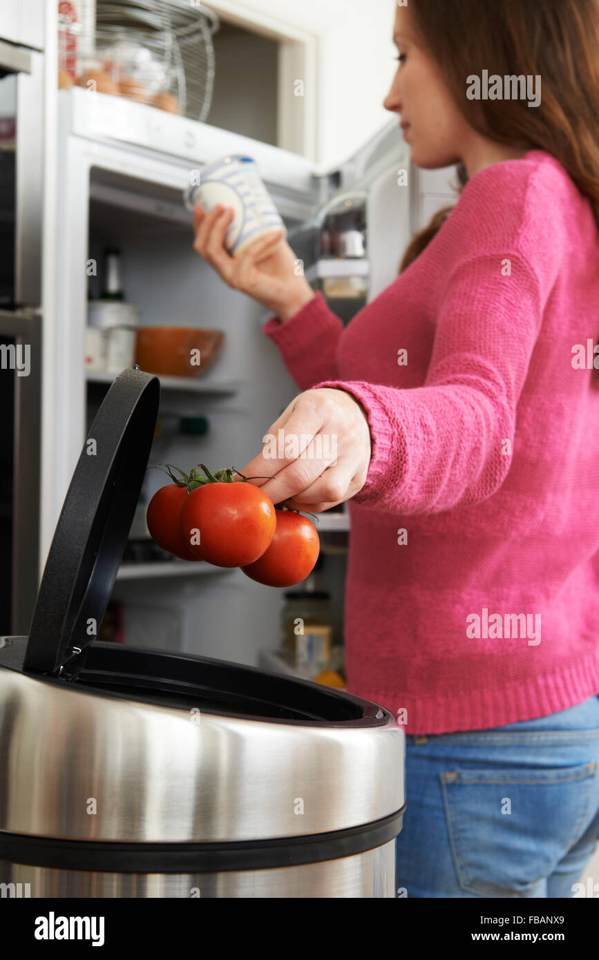 Woman Throwing Away Out Of Date Food In Refrigerator Stock Photo