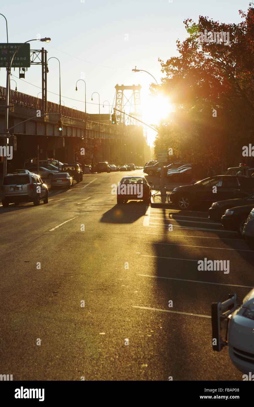 View down a Lower East Side backstreet by the Williamsburg Bridge as the sun rises and flares into the camera lens Stock Photo
