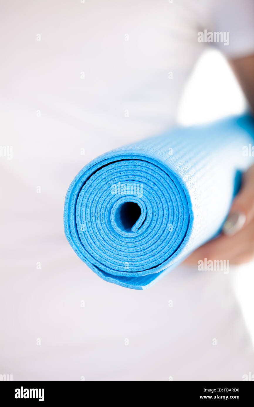Close up, white woman hands holding folded blue yoga, pilates mat