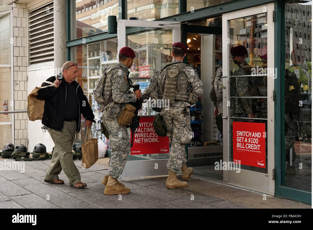 A man follows heavily armed National Guard troopers on patrol into a shop in Baltimores inner harbor, April 30, 2015. Stock Photo