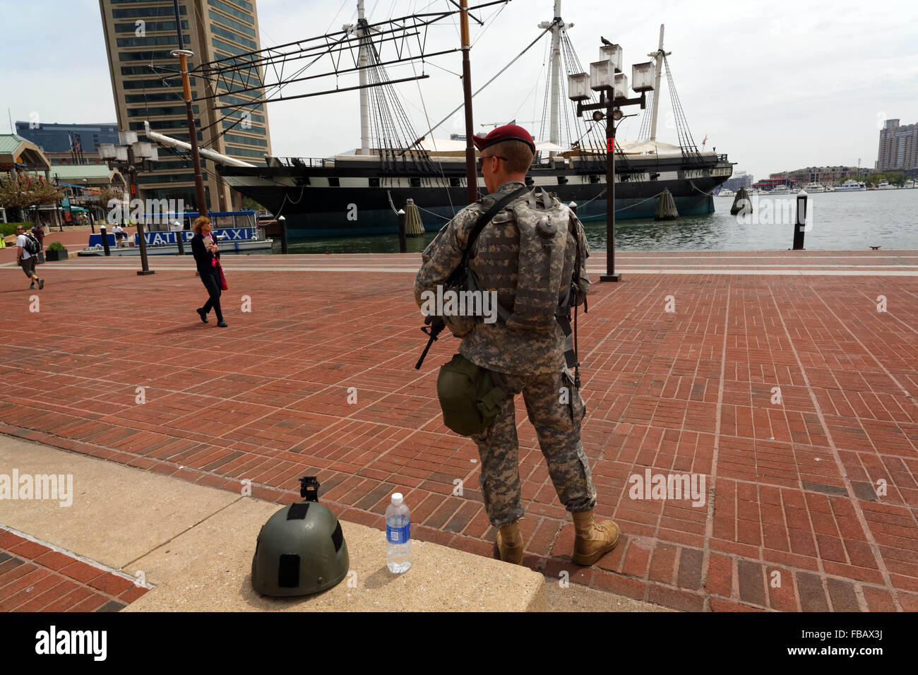 A National Guardsman in Baltimores inner harbor, with the U.S.S. Constitution, the Worlds oldest floating  commissioned warship. Stock Photo
