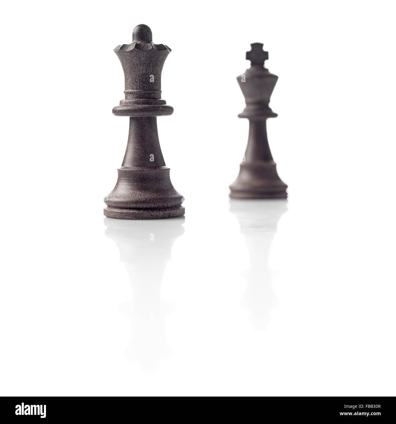 Chess. Black Queen and King out of focus and their shadows reflection on white background. Winner, power, competition or leaders Stock Photo