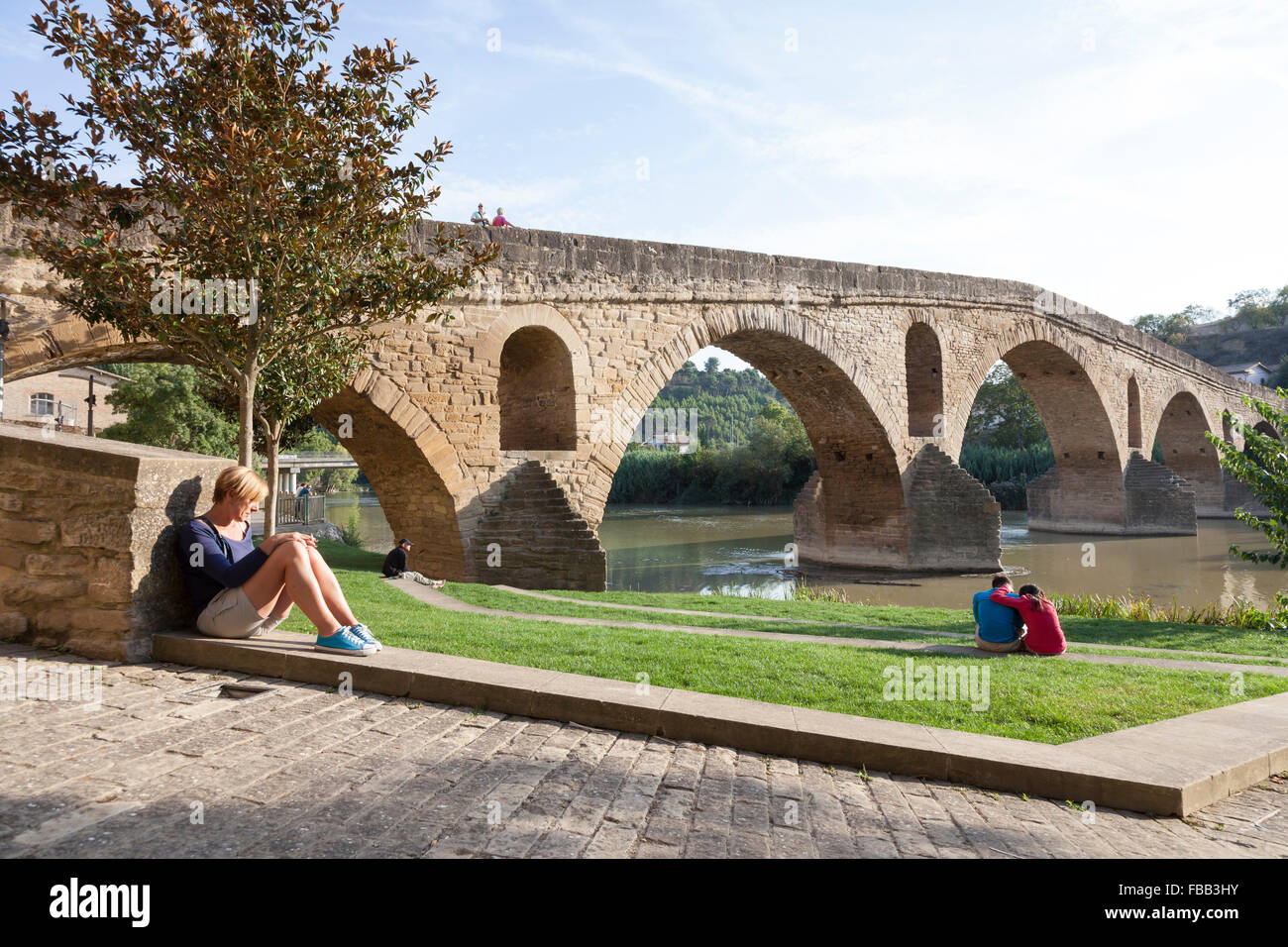 Pilgrims resting near the Medieval bridge in Puente La Reina - Navarre, Spain. Stock Photo