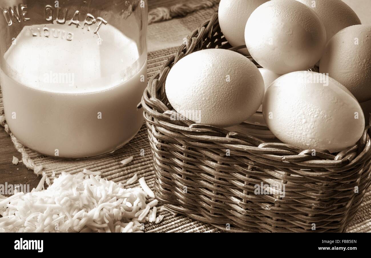 Fresh From The Farm. Antique carafe of fresh milk with eggs and cheese in retro styled background. Stock Photo
