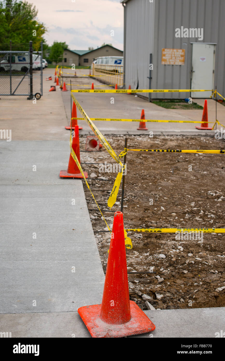 Safety orange road cones and caution tape surround new construction areas Stock Photo