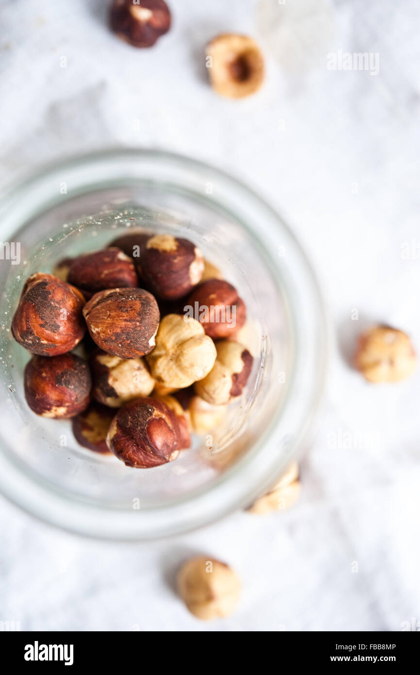 Toasted hazelnuts in a jar and on white linen Stock Photo