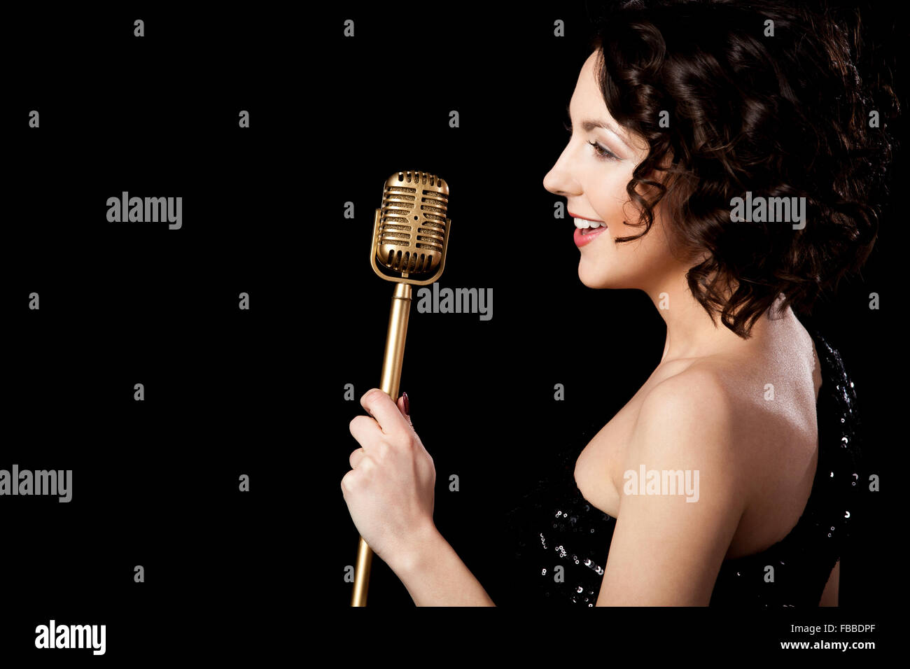 Elegant young female singer in shiny black evening outfit singing with