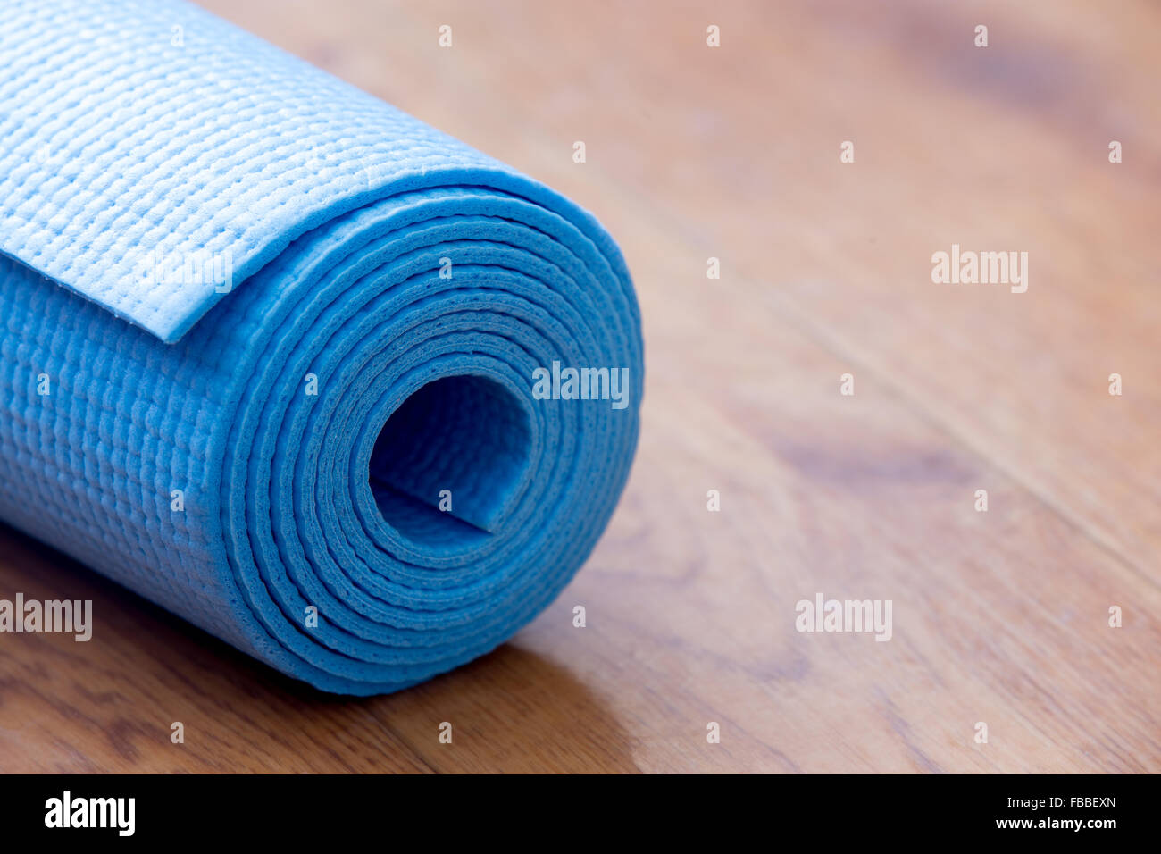 Close up of folded blue non-slip yoga, pilates mat on the floor