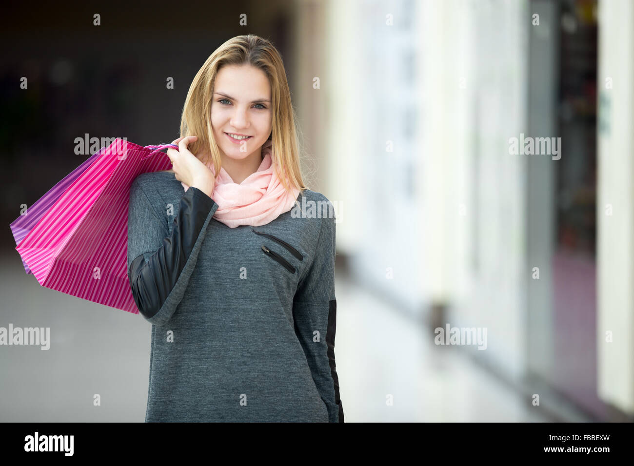Smiling good-looking teenage girl on shopping, walking in supermarket with paper bags, copyspace Stock Photo