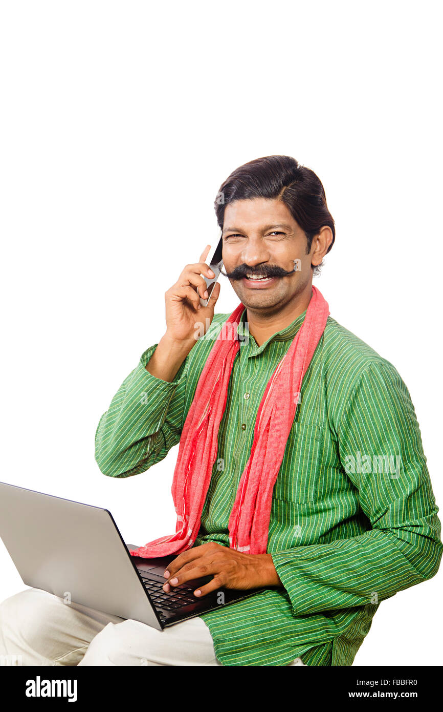 1 indian Rural man sitting laptop and talking Mobile Phone Multi Tasking Stock Photo