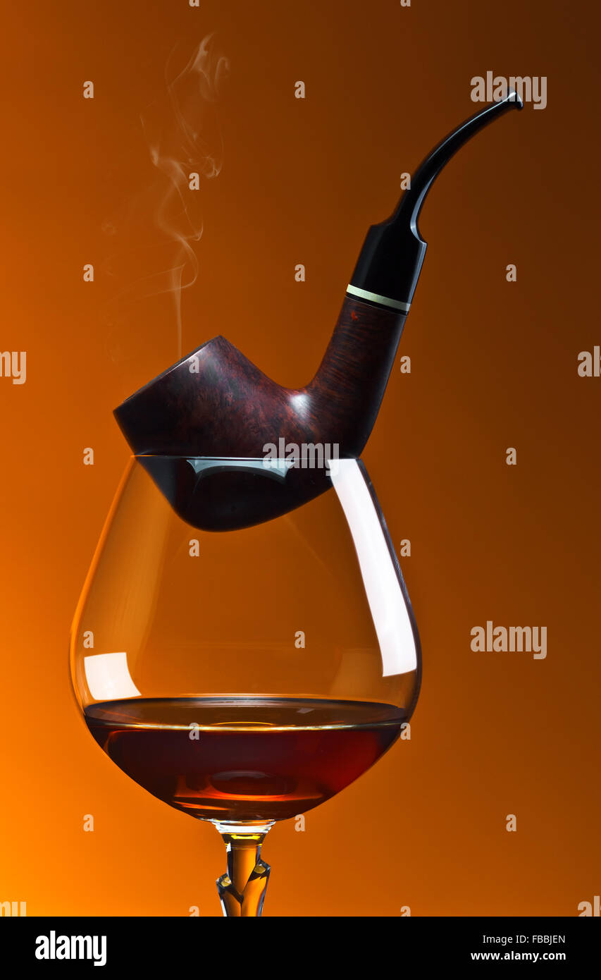 pipe and snifter with brandy on orange background Stock Photo Alamy