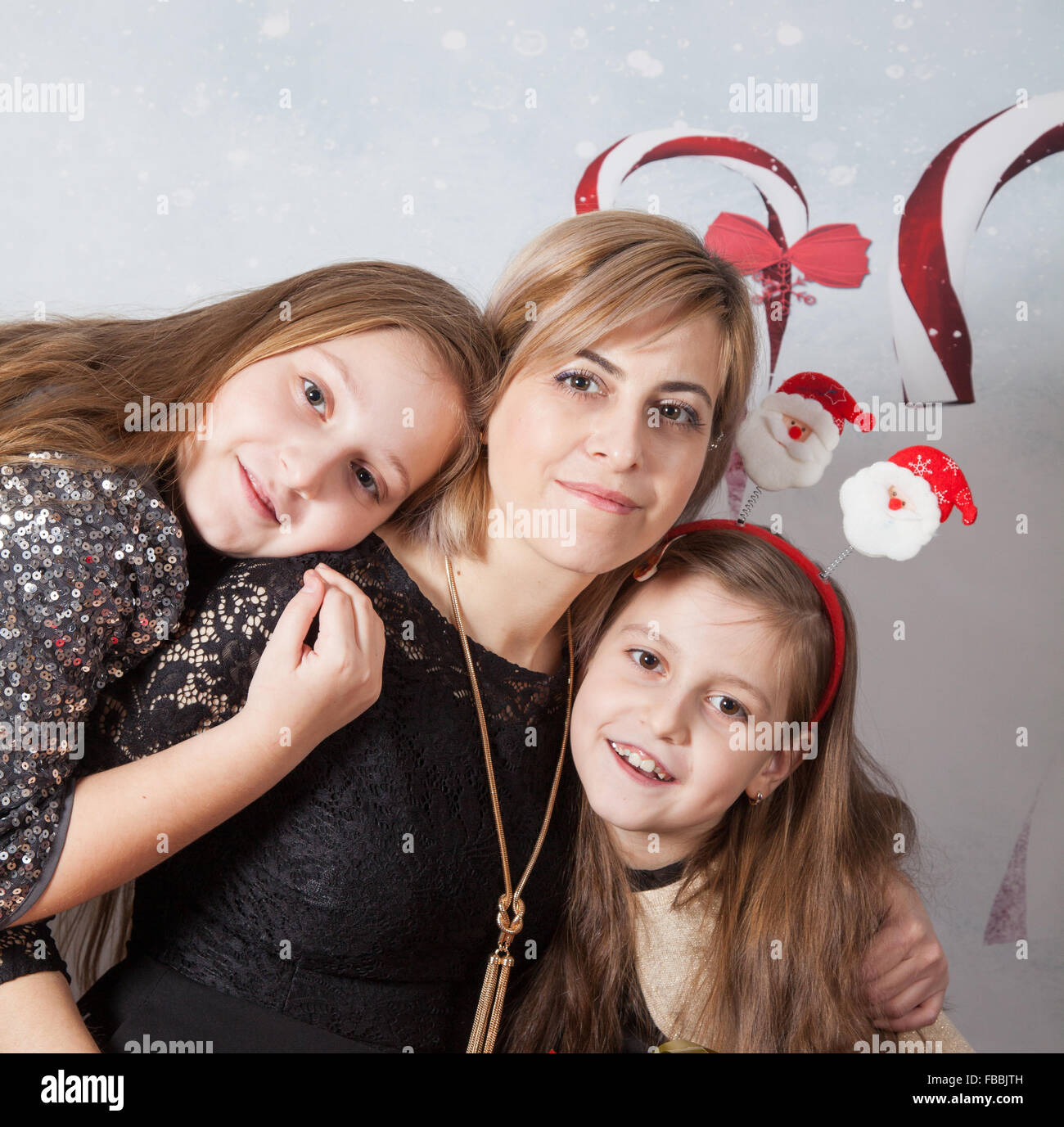 Portrait of a beautiful mother with her 2 daughters, Christmas themed, studio shot. Stock Photo