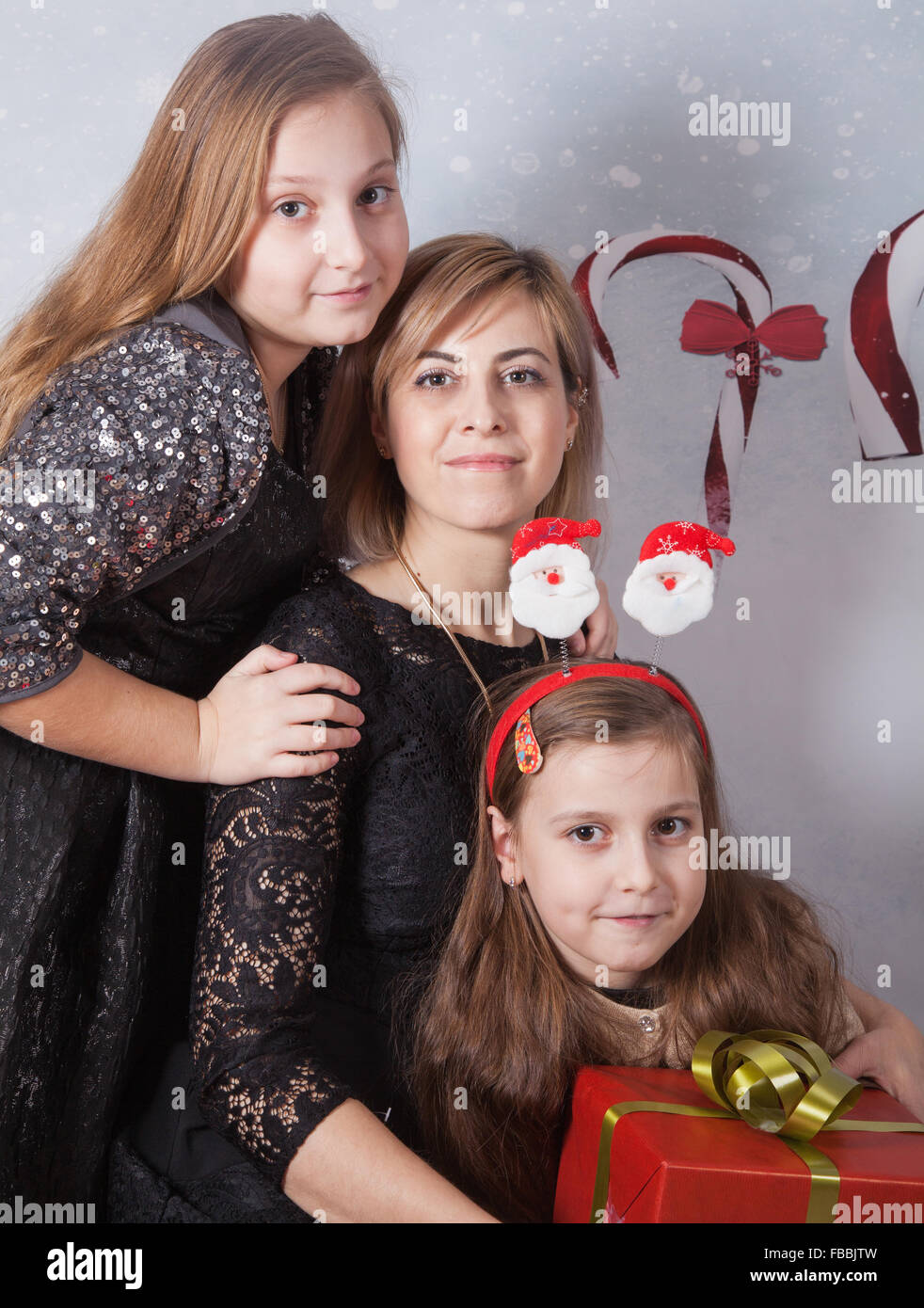 Portrait of a beautiful mother with her 2 daughters, Christmas themed, studio shot. Stock Photo