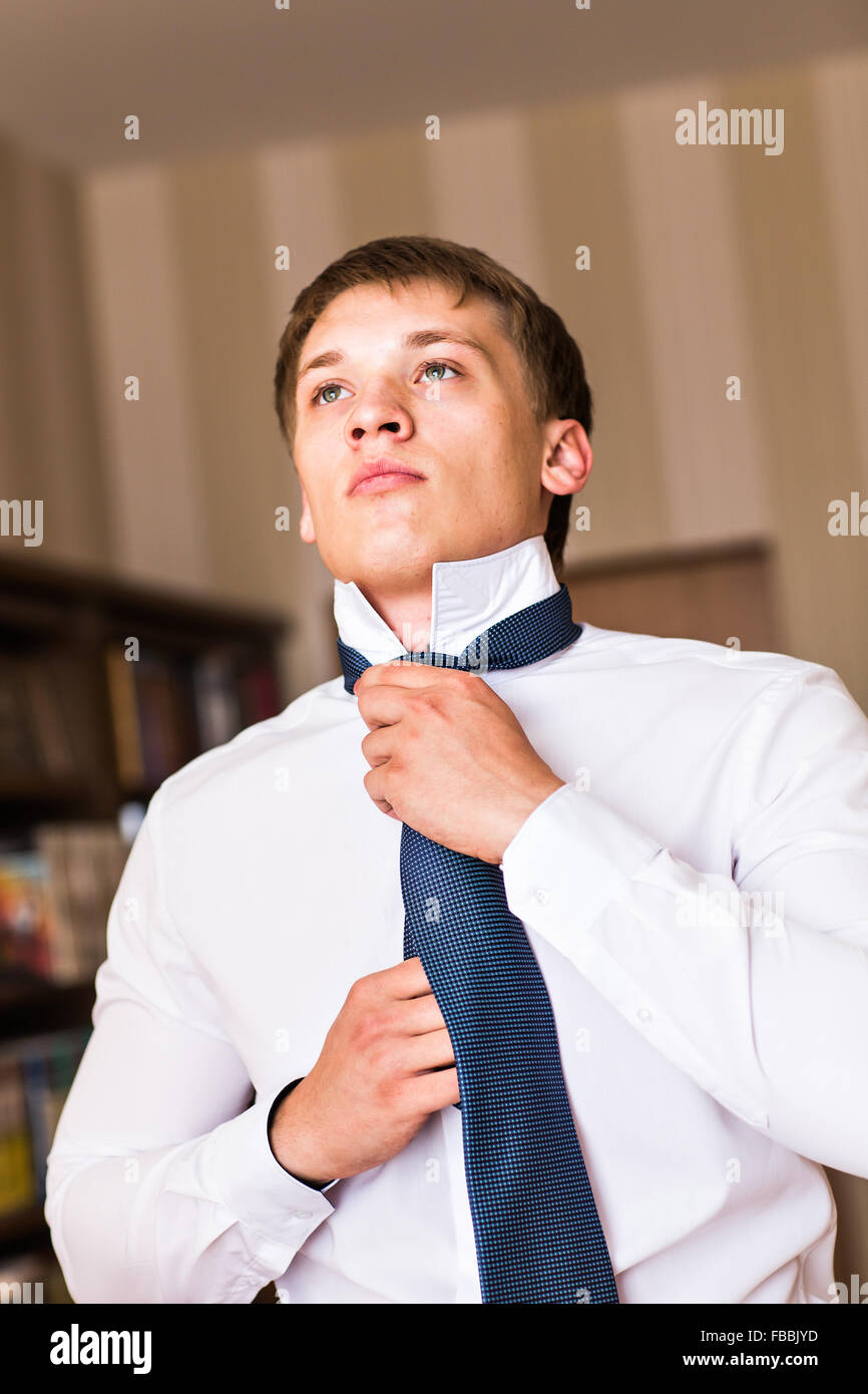 Portrait of a man adjusting his shirt and tie Stock Photo - Alamy