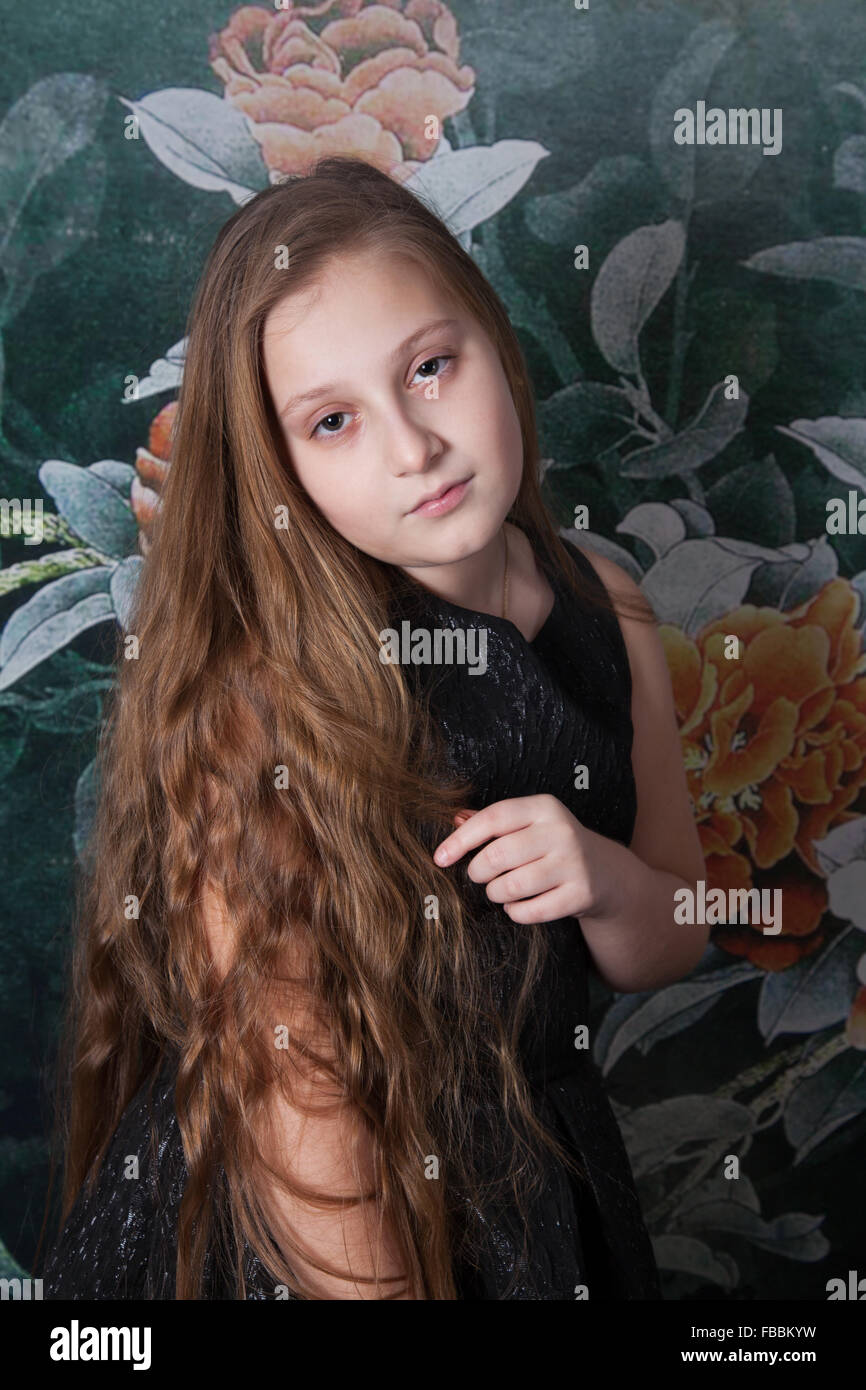 Portrait of a 10 year old girl over floral background, studio shot. Stock Photo