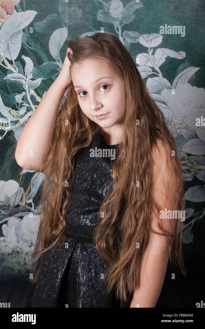 Portrait of a 10 year old girl over floral background, studio shot. Stock Photo