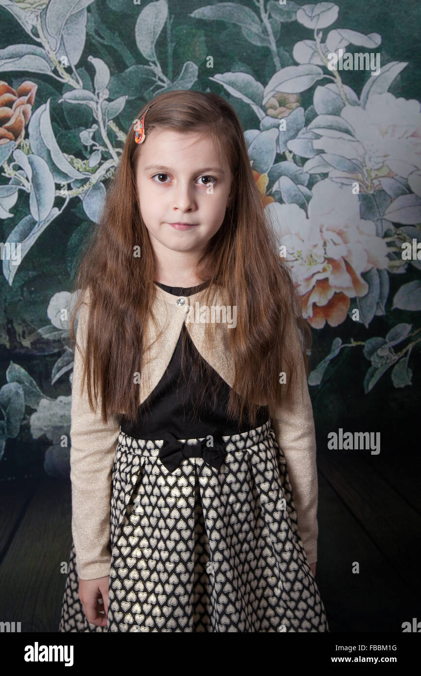 Portrait of a 8 year old girl, nicely dressed over flower background, studio shot. Stock Photo