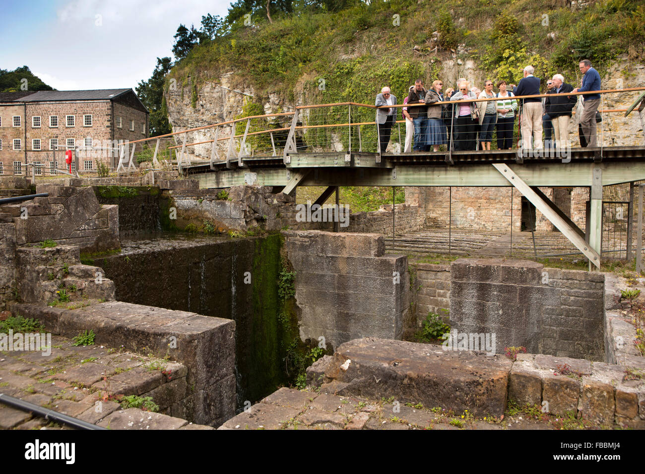 UK, England, Derbyshire, Cromford Mill, visitors on guided tour above waterwheel pit Stock Photo