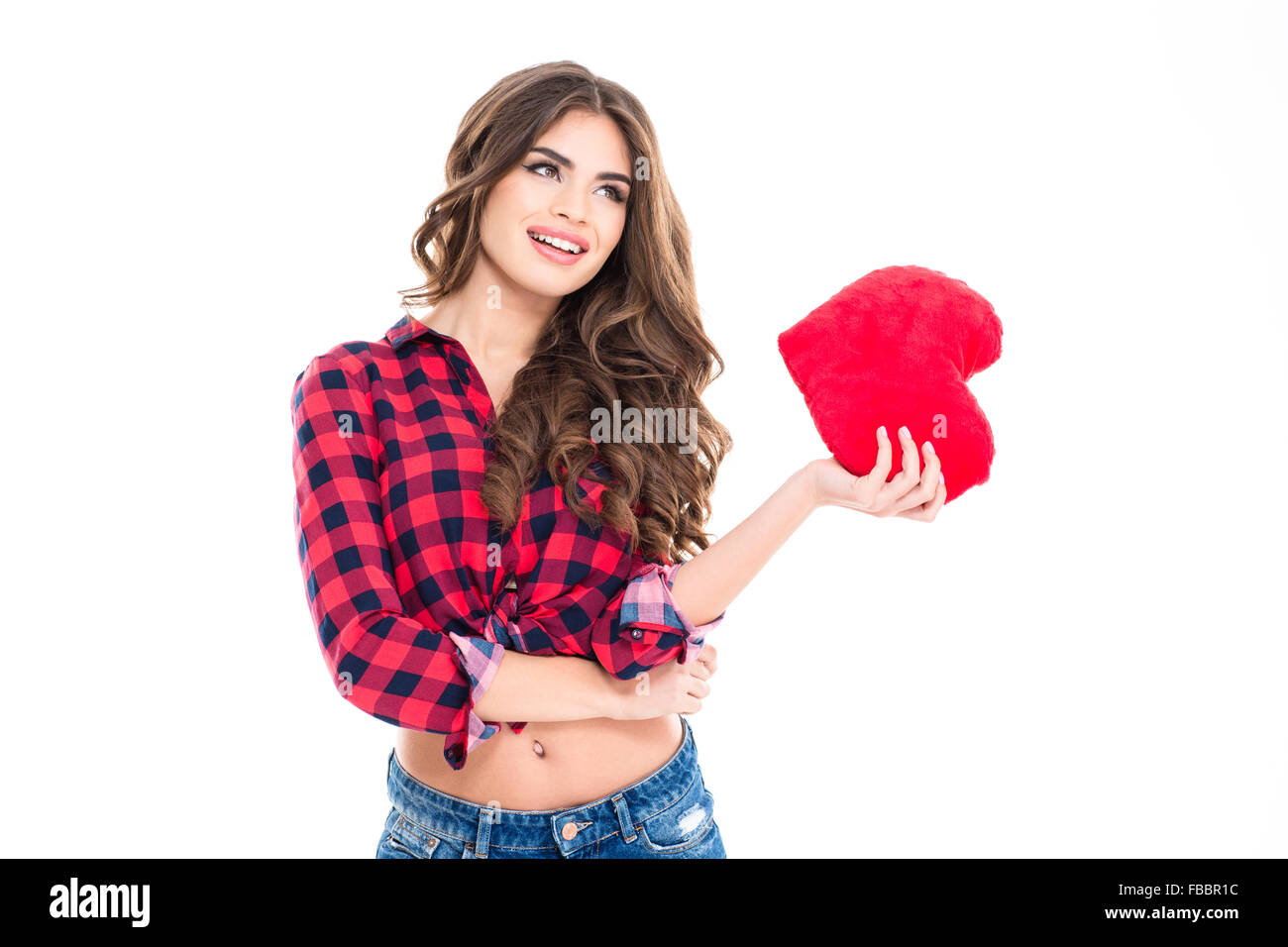 Beautiful happy young woman with long curly hair holding red heart in hand standing over white background Stock Photo