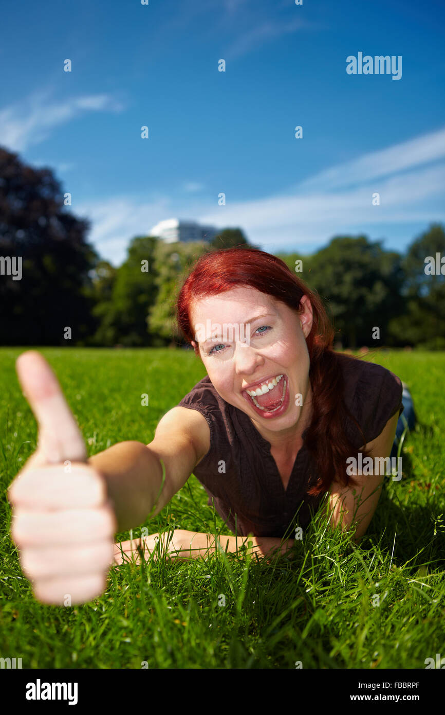 Successful woman holding her thumbs up in nature Stock Photo - Alamy
