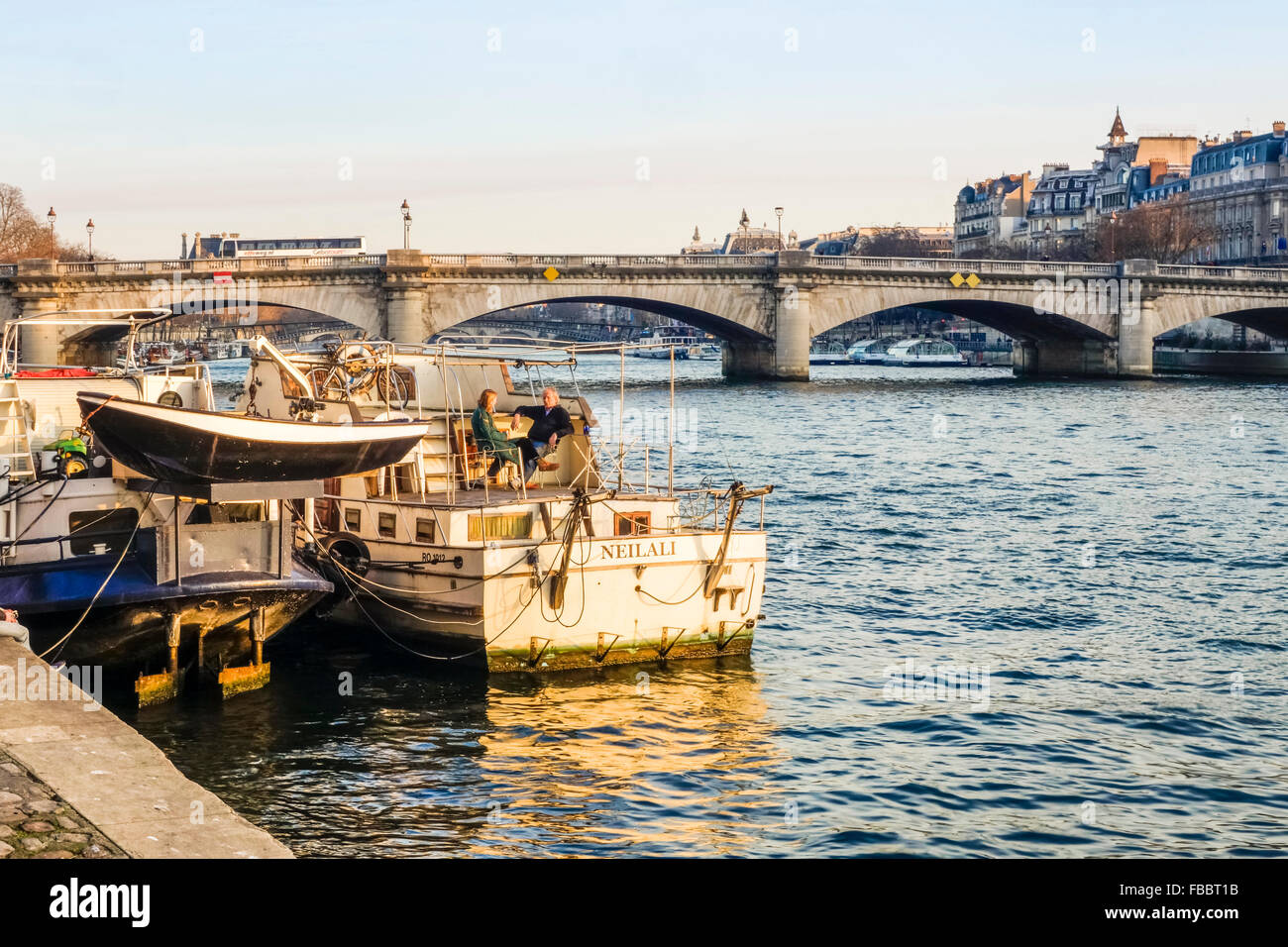 Seine river with barges and couple on terrace on boat, Pont de la Concorde, bridge behind, Paris France. Stock Photo
