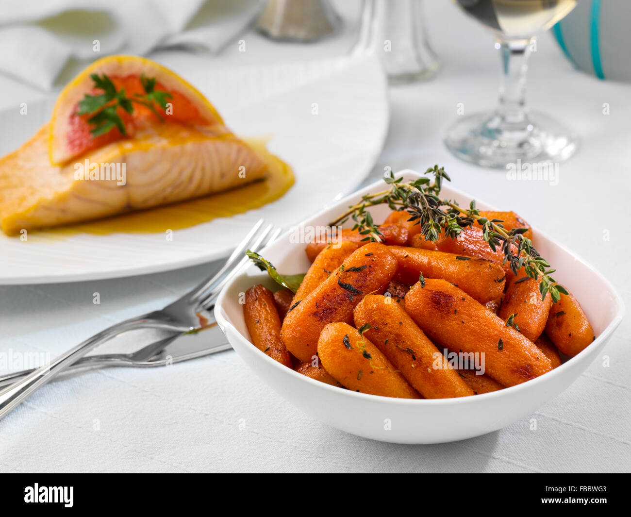Glazed carrots with seared salmon behind Stock Photo Alamy