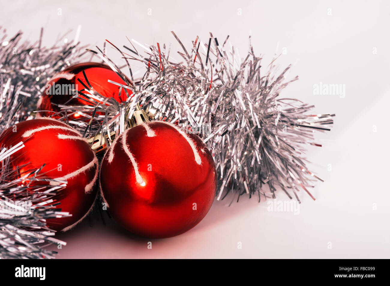 Three red baubles and silver tinsel. Stock Photo