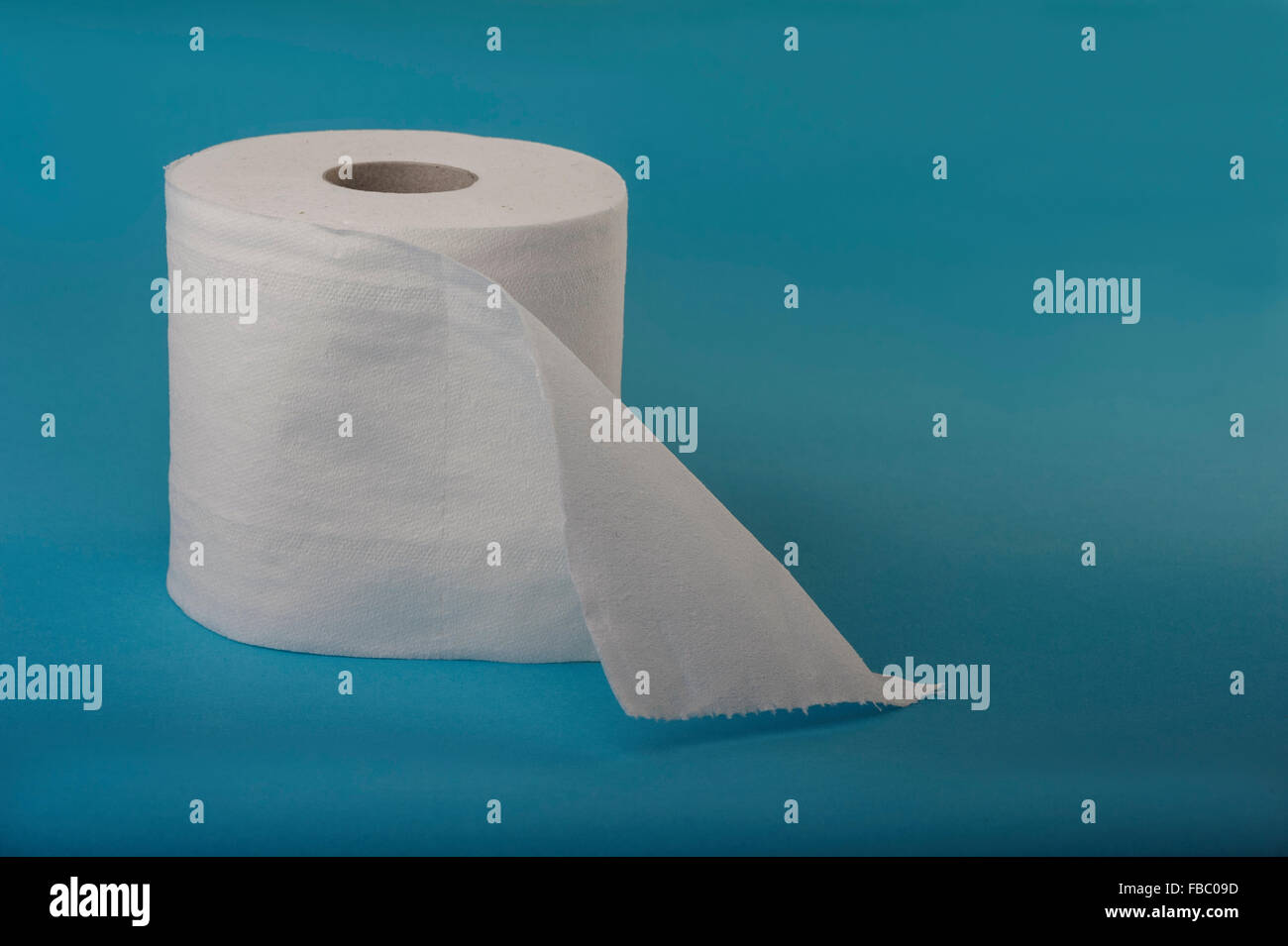 Single roll of toilet tissue on a blue background. Stock Photo