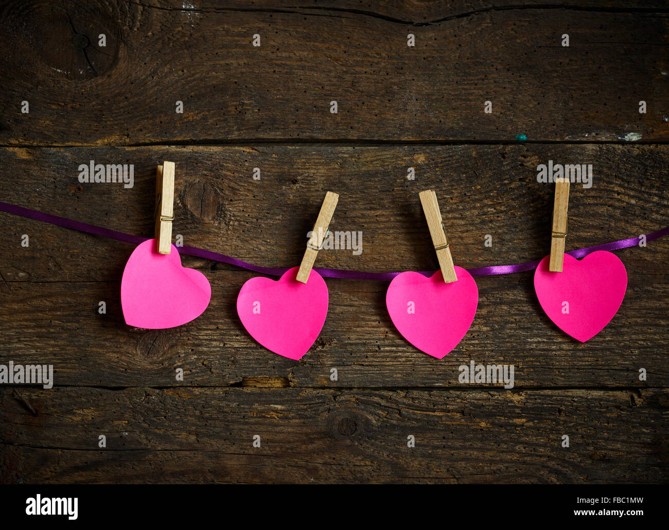 Pink heart paper cut out with clothes pins. Image of Valentines day season. Stock Photo