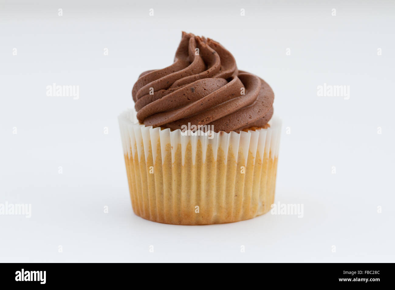A chocolate cupcake with swirled frosting on an isolated white background. Stock Photo