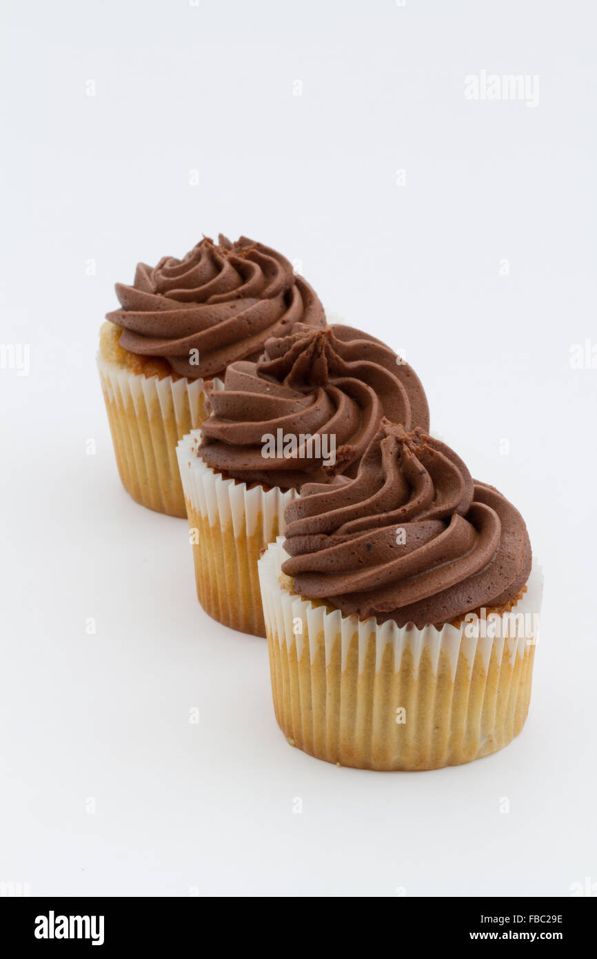 Three chocolate cupcakes in a row on an isolated white background. Portrait orientation. Stock Photo