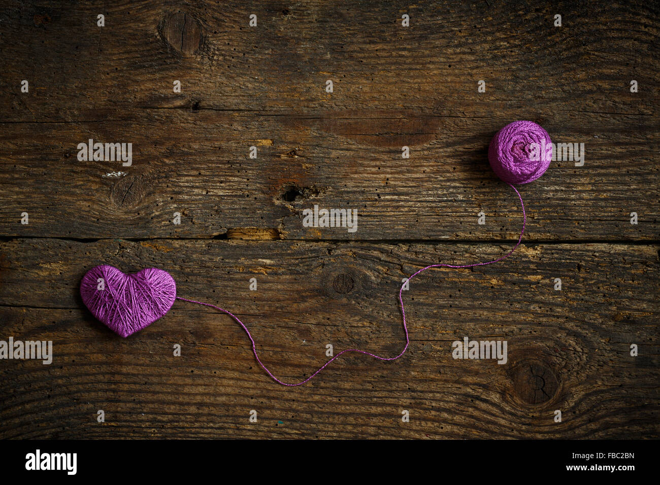 Purple Heart with a ball of thread on on old shabby wooden background ...
