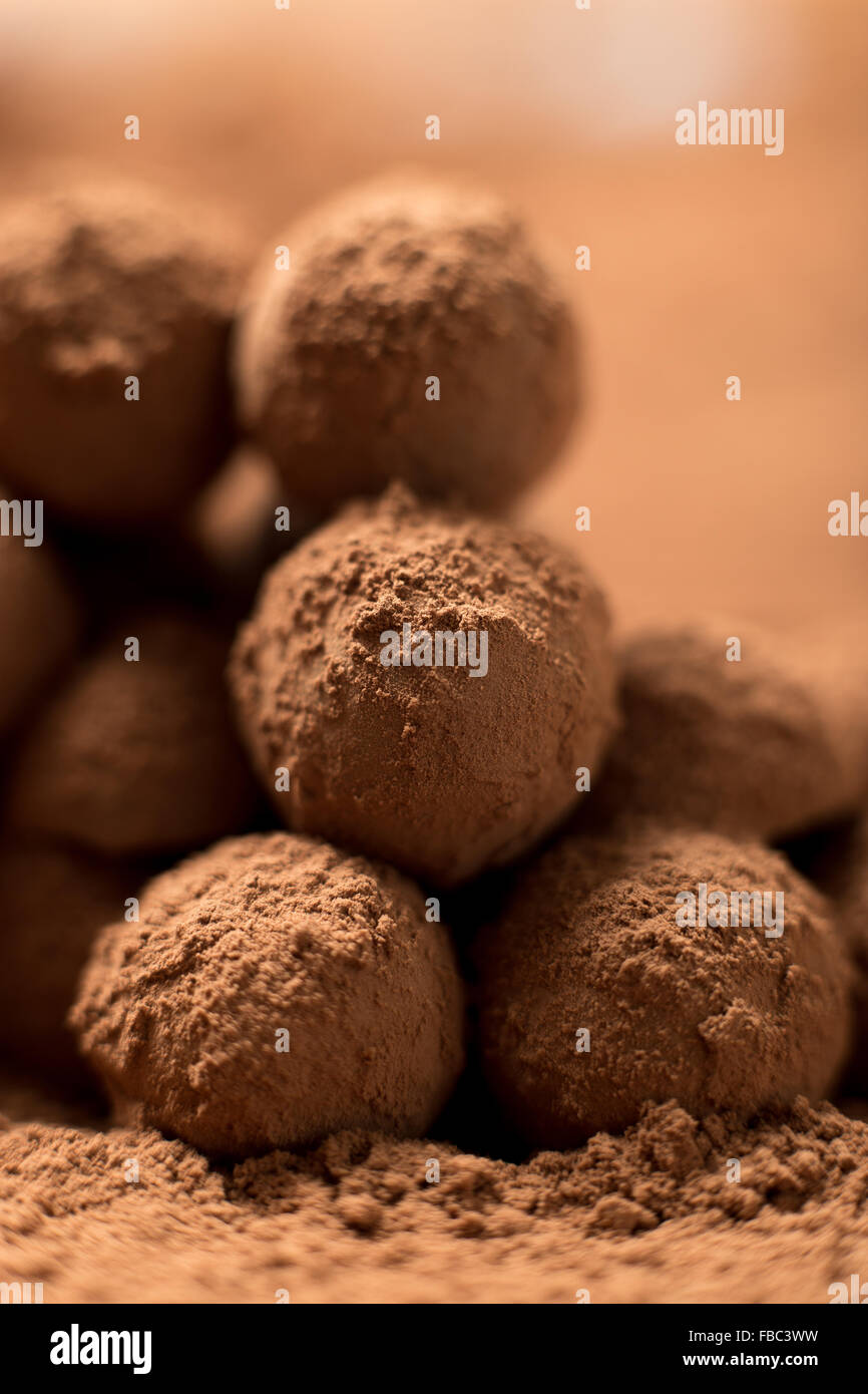 Homemade cooking. Stack of appetizing black chocolate round truffles covered in cocoa dust. Shallow depth of field, close up Stock Photo