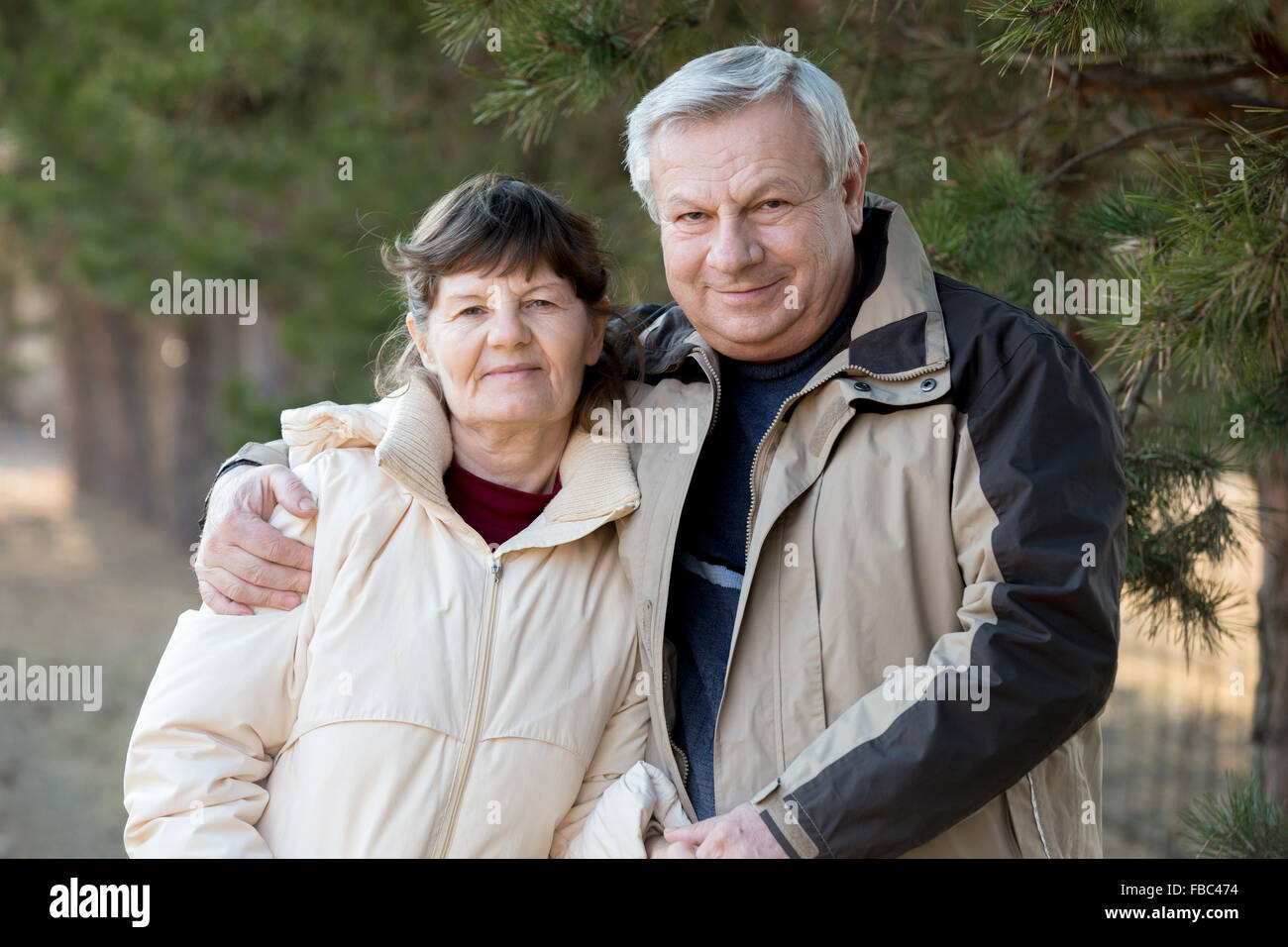 Portrait of elder couple on a walk in park, senior man hugging his wife with gentleness Stock Photo