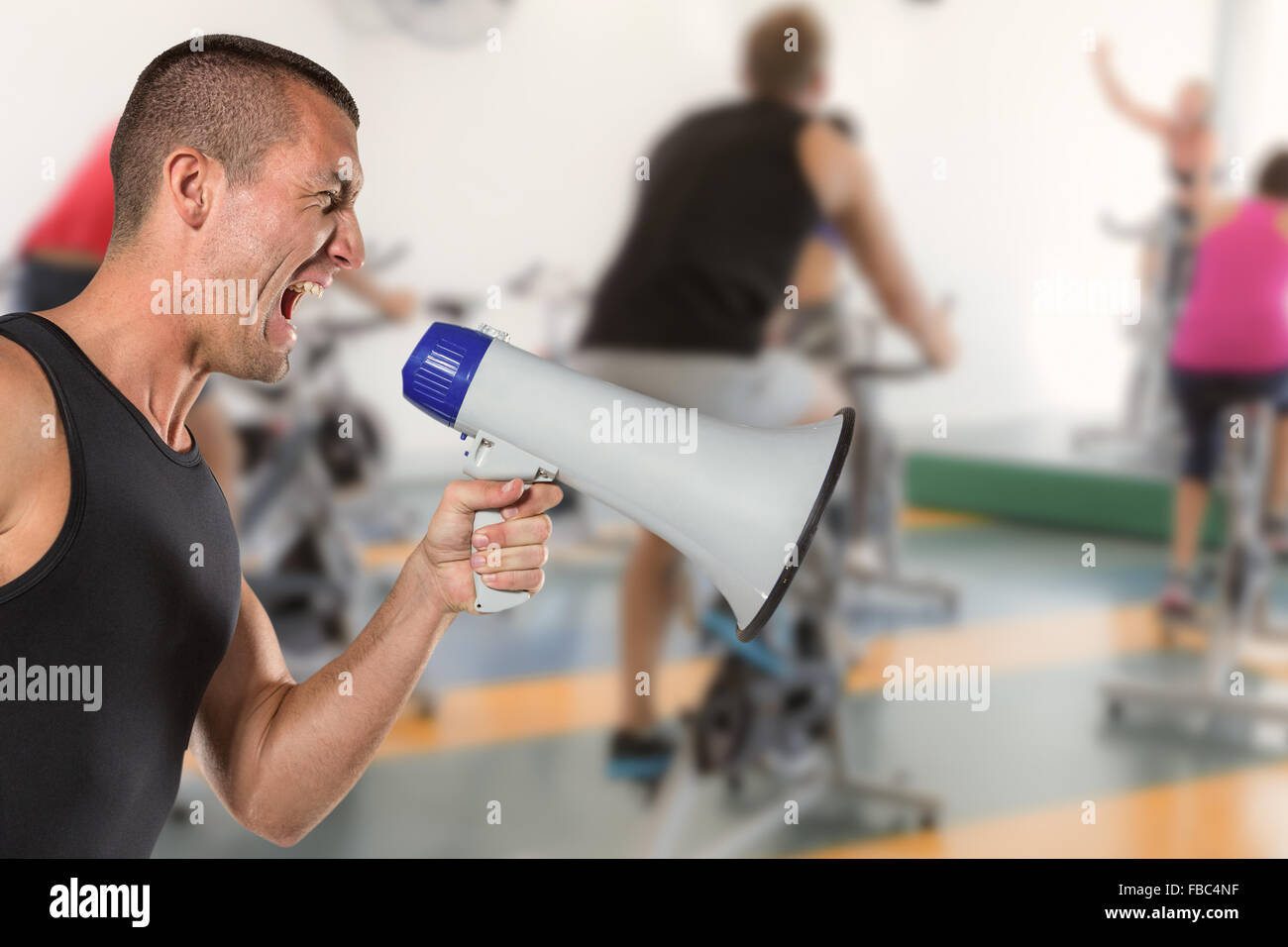 Composite image of irritated male trainer yelling through megaphone Stock Photo