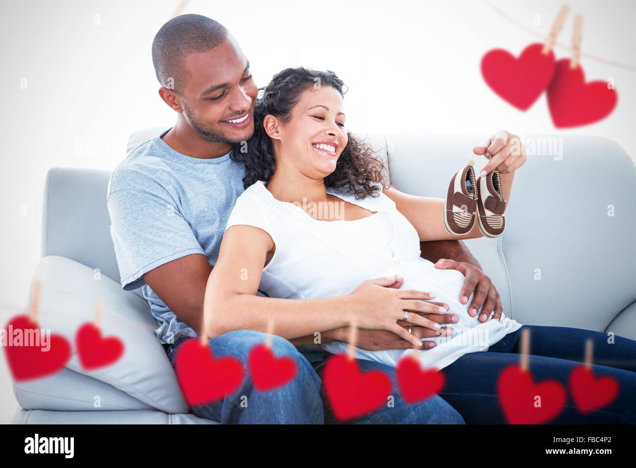 Composite image of couple with baby shoes Stock Photo