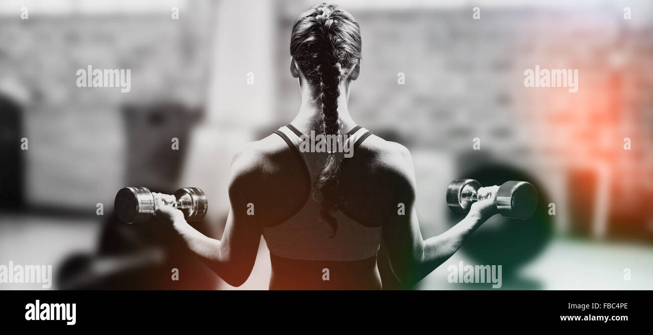 Composite image of rear view of braided hair woman lifting dumbbells Stock Photo
