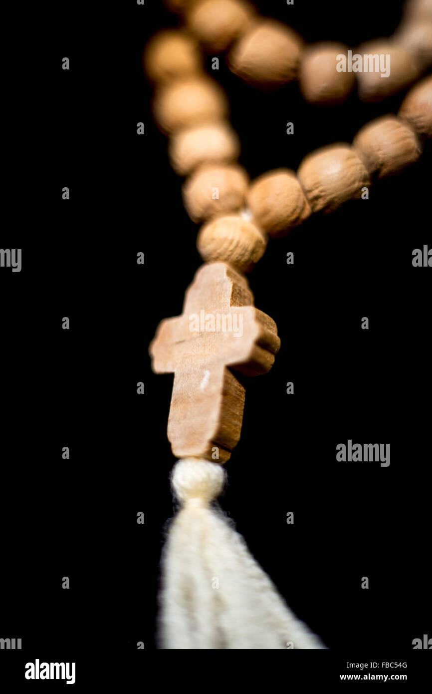Christian wooden prayer beads with cross on black background Stock Photo