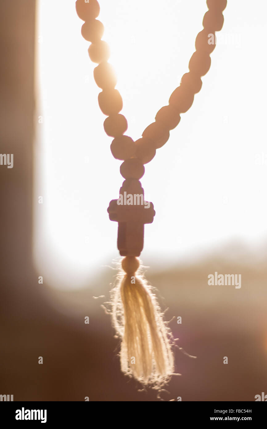 Christian wooden prayer rosary with cross against the sun Stock Photo