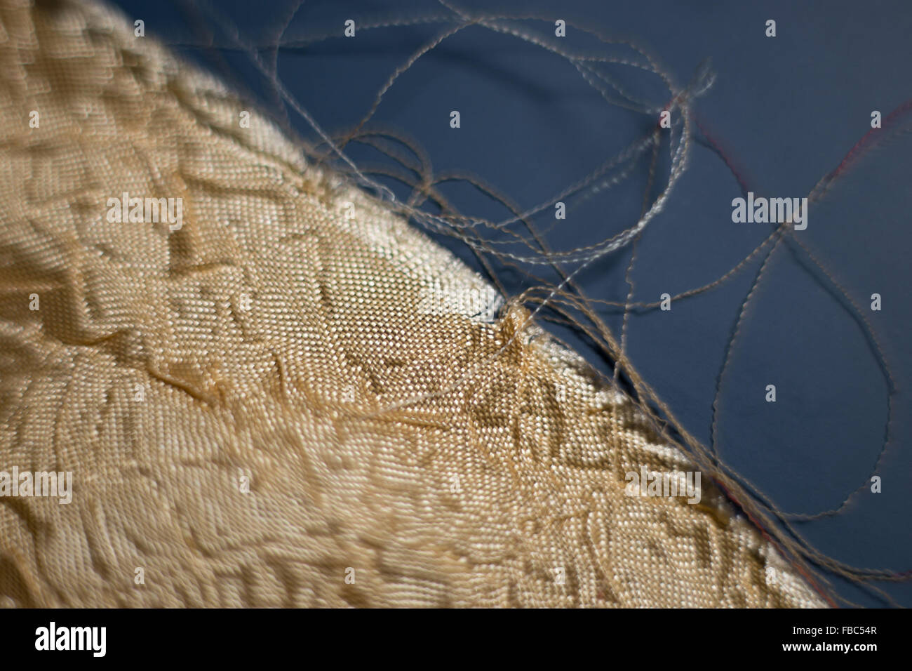 Torn edge of yellow fabric on blue background, shallow depth of field Stock Photo