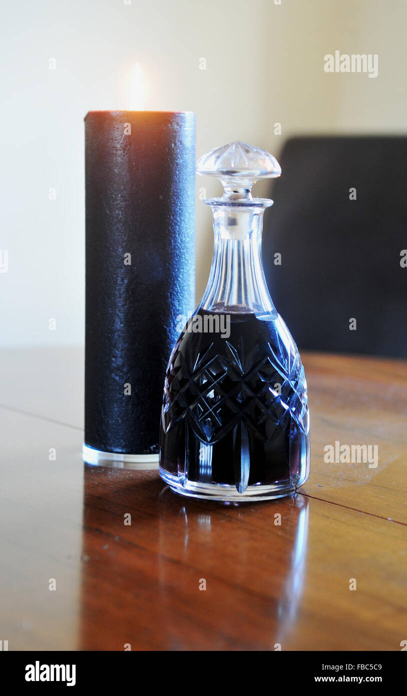 Decanter of port and a black candle with flame alight Stock Photo