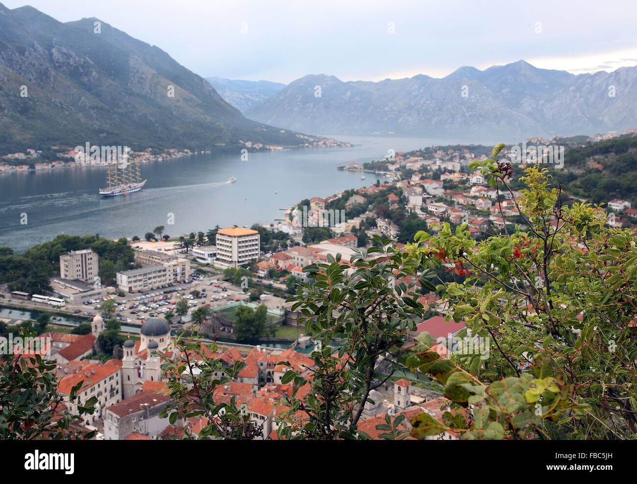 Tall ship pictured in the Bay of Kotor alongside the medieval port town of Kotor in Montenegró Stock Photo