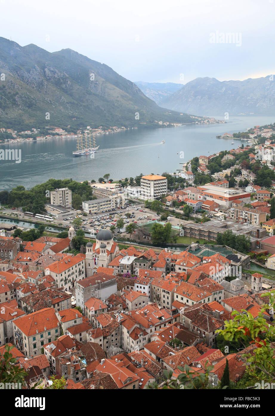 Tall ship pictured in the Bay of Kotor alongside medieval port town of Kotor, Montenegró. Stock Photo