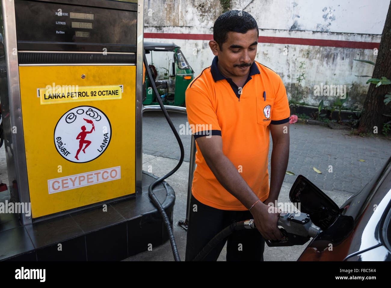 A petrol pump attendant fills up with fuel at one of the many Government-owned Ceypetcc outlets in Kandy, Sri Lanka. Stock Photo